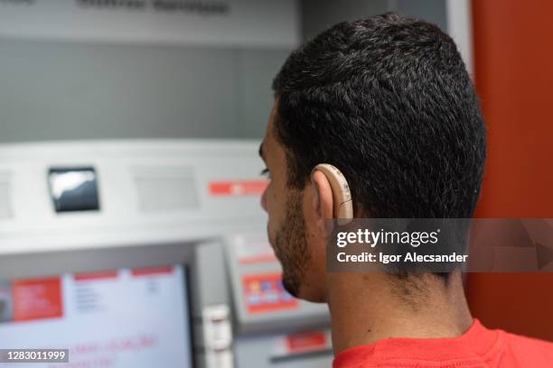 deaf young man at bank atm - hearing loss at work stock pictures, royalty-free photos & images