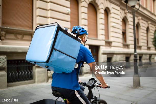 rear view of a young caucasian delivery man working - delivery person stock pictures, royalty-free photos & images