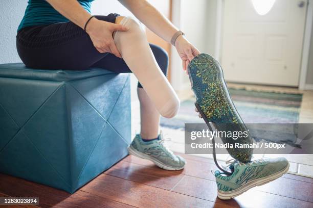 caucasian woman amputee putting on her prosthetic leg,poulsbo,washington,united states,usa - amputee women stockfoto's en -beelden