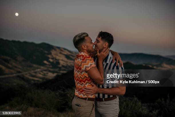 young caucasian lgbtqi couple kissing each other romantically - gay kiss stock-fotos und bilder