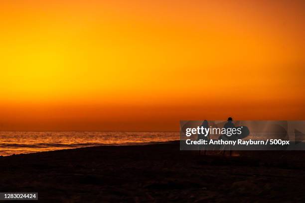 sunset view of two surfers near the ocean,el pescadero,baja california sur,mexico - baja california peninsula stock pictures, royalty-free photos & images