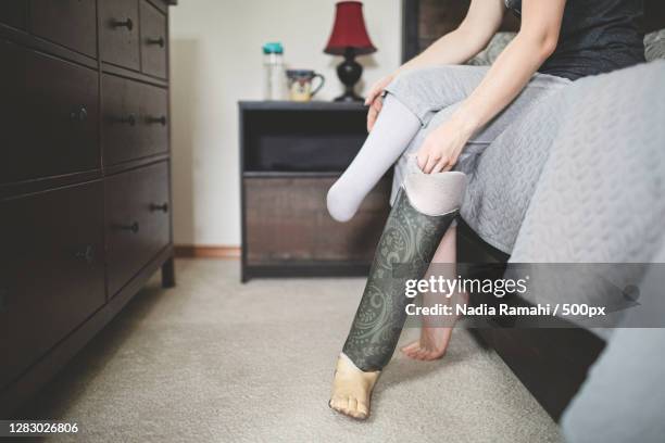 female amputee sitting on edge of bed,poulsbo,washington,united states,usa - amputee home stock pictures, royalty-free photos & images