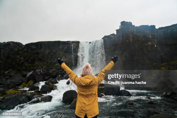 unrecognizable traveler relaxing near waterfall with outstretched arms - thingvellir national park stock pictures, royalty-free photos & images