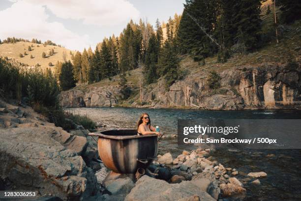 caucasian woman soaking in a tub next to riverside,stanley,id,united states,usa - washing tub stockfoto's en -beelden