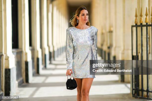 Maria Rosaria Rizzo wears large earrings from Giovanni Raspini, a sequined shiny glittering short dress with long sleeves from "Alcoolique", a Prada...