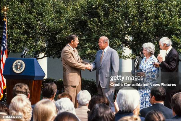 Newly sworn-in American politician and US President Ronald Reagan and US Secretary of State George P Shultz shake hands during a ceremony in the...