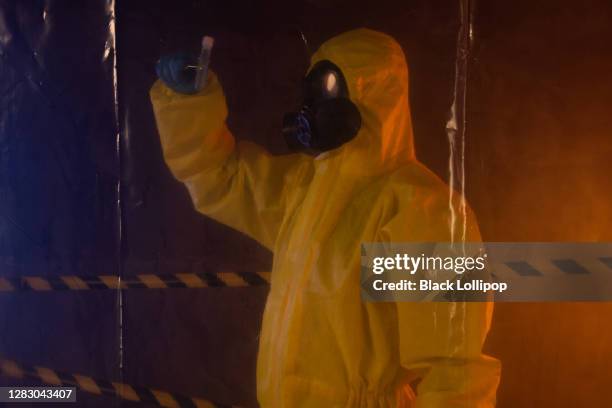 specialist in hazmat suit behind protective plastic wall carrying test tube. military medical confidential experiment. - teoria da conspiração imagens e fotografias de stock