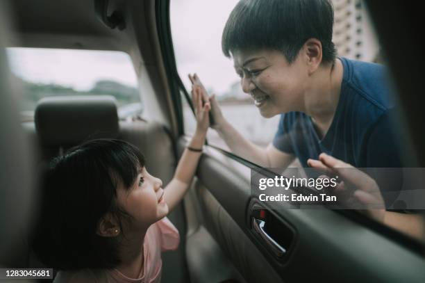 asian chinese young girl inside car looking at her mother through window happily touching - kid looking through window stock pictures, royalty-free photos & images