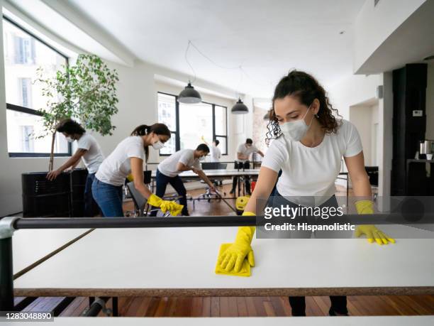group of professional cleaners cleaning an office space wearing facemasks - disinfection service stock pictures, royalty-free photos & images