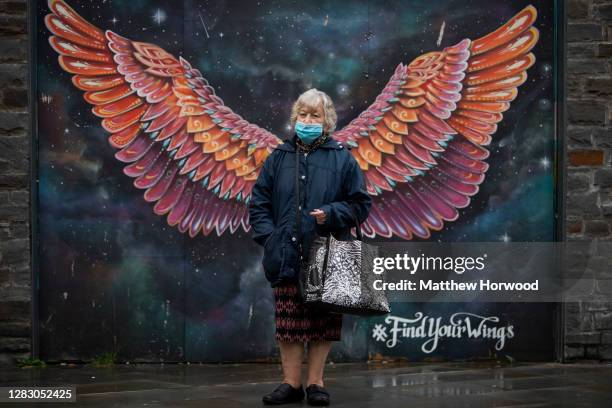 Woman poses for a photograph in front of a pair of wings painted onto a wall near Friars Walk shopping centre on October 30, 2020 in Newport, Wales....