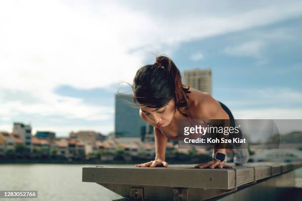 asiatische frau macht push-ups in der städtischen natur - dekolleté stock-fotos und bilder