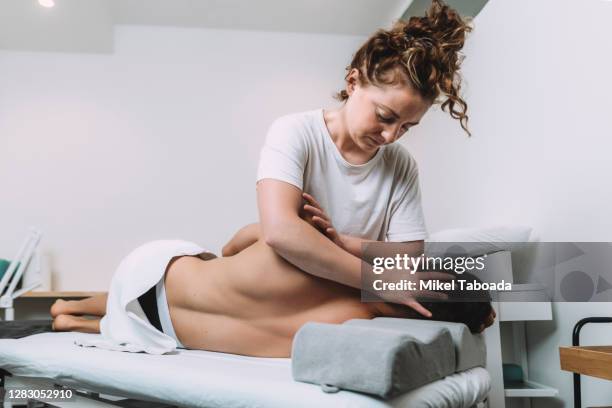 female physical therapist treating the injury to a man - osteopathie stockfoto's en -beelden