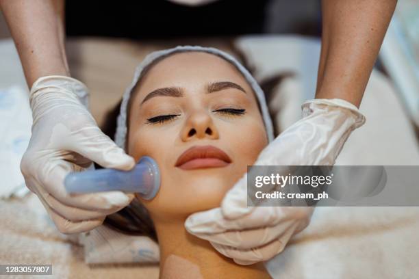 woman having a facial cupping treatment in the beauty clinic - mão em forma de concha imagens e fotografias de stock