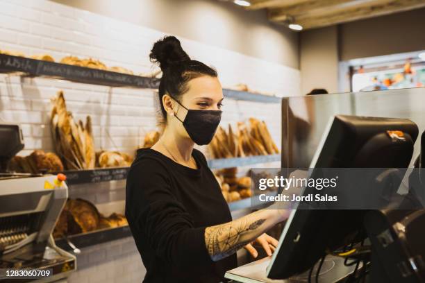 baker woman typing the cash register machine in a bakery - small business mask stock pictures, royalty-free photos & images