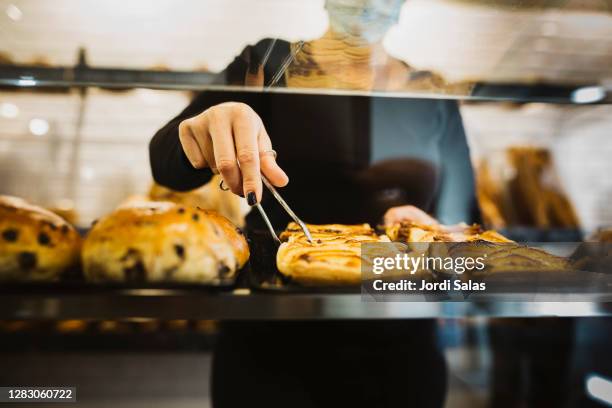 baker choosing pastry in the vitrine of a bakery - boulangerie vitrine stock pictures, royalty-free photos & images