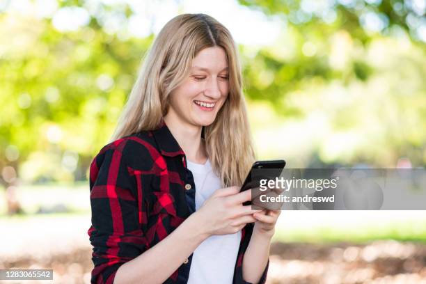 uma mulher loira enviando mensagem de texto no smartphone - discar - fotografias e filmes do acervo