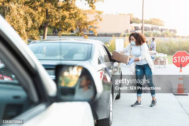 de vrijwilligers van de vrouw bij drive-through voedselaandrijving - vrijgevigheid stockfoto's en -beelden