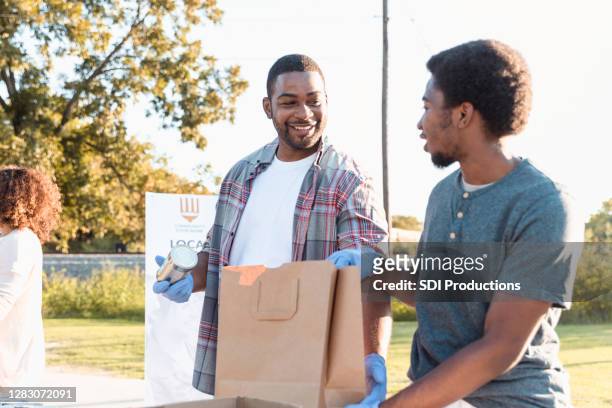 father and son volunteer during charity drive - giving tuesday stock pictures, royalty-free photos & images
