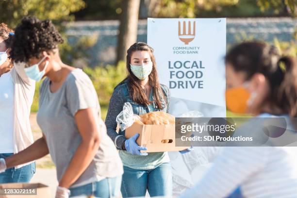 young woman volunteers at food drive during covid-19 - charity and relief work stock pictures, royalty-free photos & images