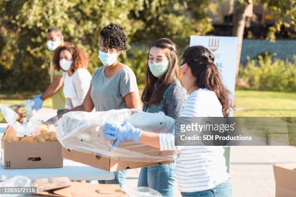 female friends volunteering during outdoor food drive - social worker mask stock pictures, royalty-free photos & images