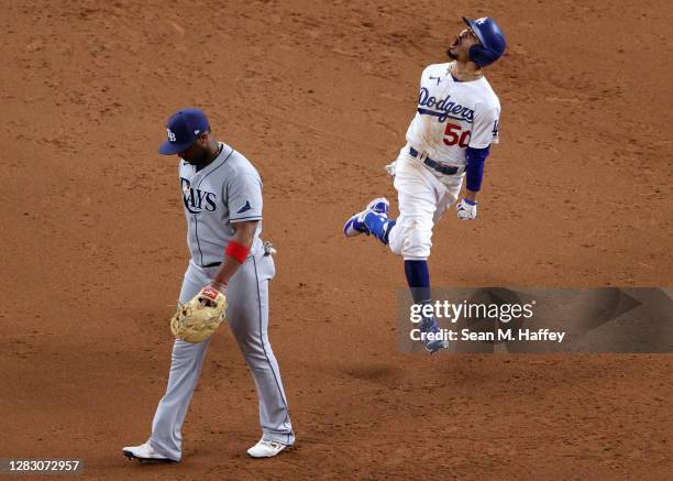 Mookie Betts of the Los Angeles Dodgers celebrates as he rounds the bases after hitting a solo home run as Yandy Diaz of the Tampa Bay Rays looks on...