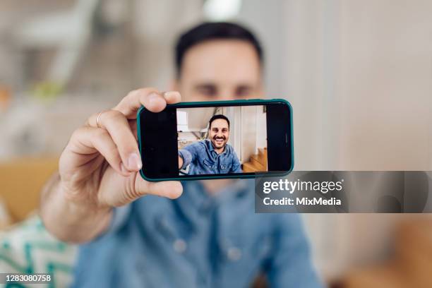 young man taking a selfie at home - selfie phone screen stock pictures, royalty-free photos & images