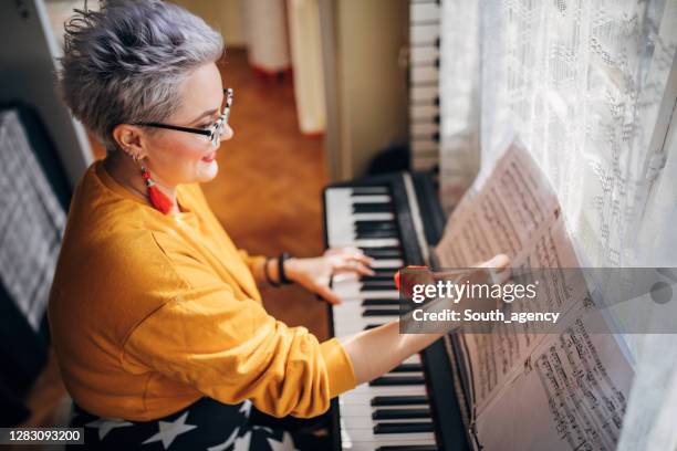 pianista femenina componiendo música en piano eléctrico en casa - electric piano fotografías e imágenes de stock