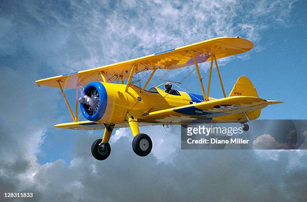 yellow stearman 5yp bi-plane flying in cloudy sky - ww2 plane stock pictures, royalty-free photos & images