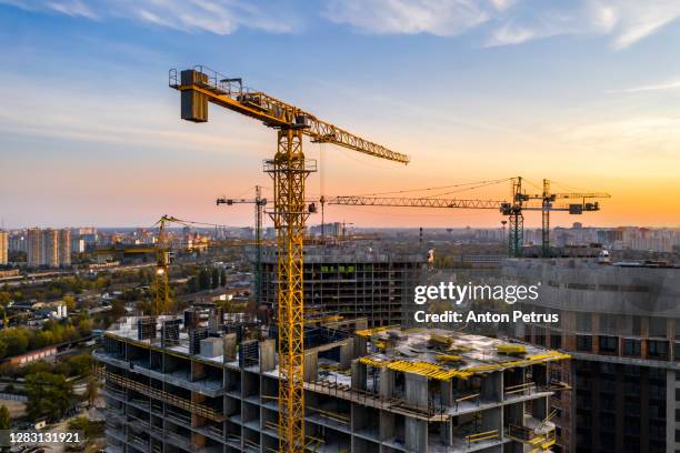 construction site with cranes at sunset. construction of an apartment building - crane building photos et images de collection