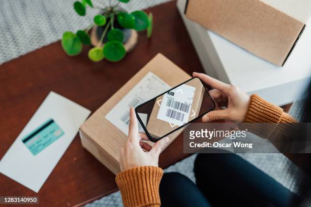 woman scanning delivery barcode on package with smart phone - sold palabra en inglés fotografías e imágenes de stock