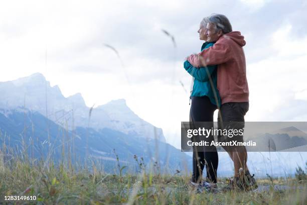 het wandelen paar ontspan in grasrijke weide in de ochtend - early retirement stockfoto's en -beelden