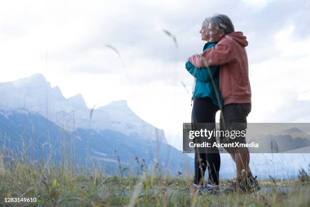 hiking couple relax in grassy meadow in the morning - early retirement stock pictures, royalty-free photos & images