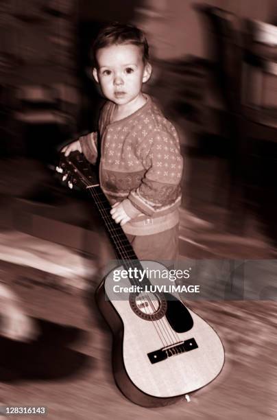 small kid holding guitar in a blurred (sepia color) - solo bambini maschi foto e immagini stock