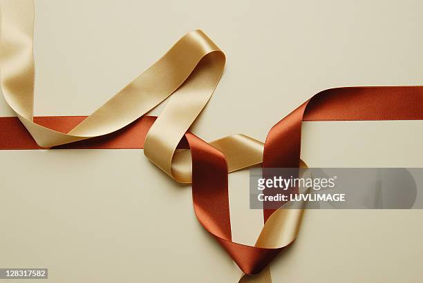 still life of wound up gold and orange ribbons - golden ribbon stock pictures, royalty-free photos & images