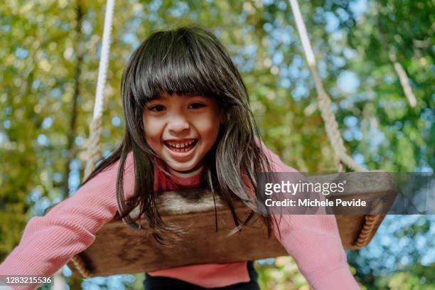 autistic korean girl swinging on a swing outdoors - autistic child stock pictures, royalty-free photos & images