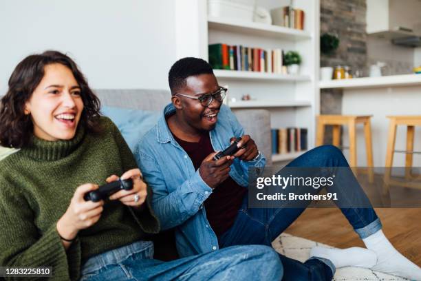 happy young diverse couple relaxing at home - entertainment centre stock pictures, royalty-free photos & images