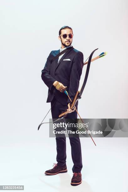 businessman holding bow and arrow - bogen pfeil und bogen stock-fotos und bilder