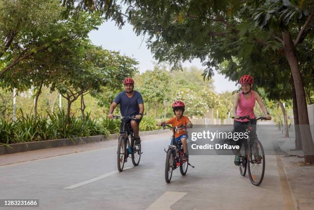 indian father, iranian mother cycling with their son - indian riding stock pictures, royalty-free photos & images