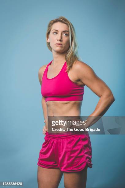 portrait of fit woman on blue background - running shorts stock pictures, royalty-free photos & images