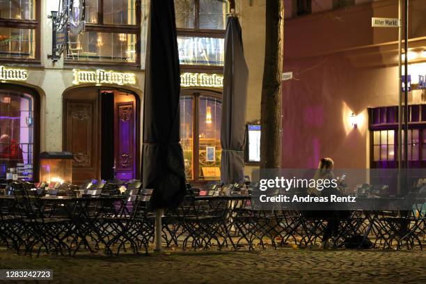 Just a few guests sit at the tables outside a pub / restaurant on the third day that local authorities mandated anew the wearing of masks outside in...