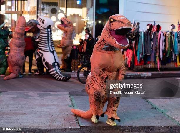 People wear inflatable T-Rex costumes in Times Square on October 31, 2020 in New York City. Many Halloween events have been canceled or adjusted with...