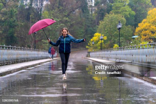 femme avec umbrella ayant l’amusement dans le jour pluvieux - meteorology photos et images de collection
