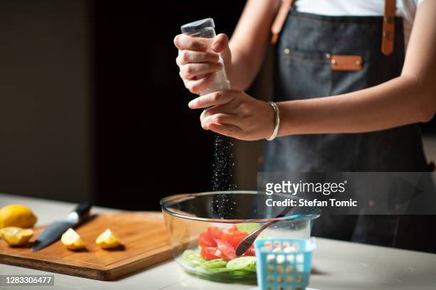 woman adding salt in cucumber tomato vegetable salad at home - adding spice stock pictures, royalty-free photos & images