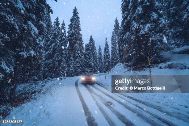 car driving on a mountain snowy road during snowfall - extreme weather snow stock pictures, royalty-free photos & images