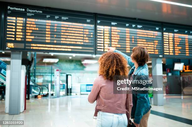pareja joven en la estación de metro mirando el tablero de información - departure board front on fotografías e imágenes de stock