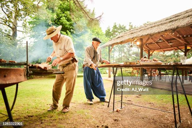two senior men barbecuing for a garden party - argentina gaucho stock pictures, royalty-free photos & images