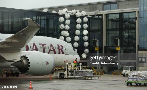 The "Pearl Necklace" sculpture, surrounding a pedestrian walkway, is seen next to a Qatar Airways airplane as it sits at a gate on the first full day...