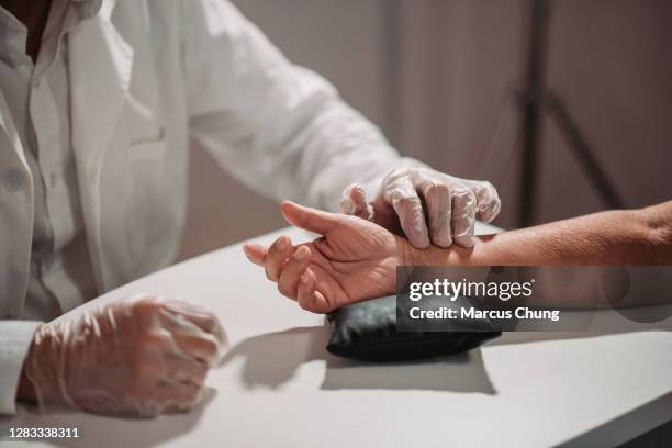 asian chinese male acupuncturists taking pulse diagnosis works for his patient at chinese medicine shop - chinese herbal medicine stock pictures, royalty-free photos & images