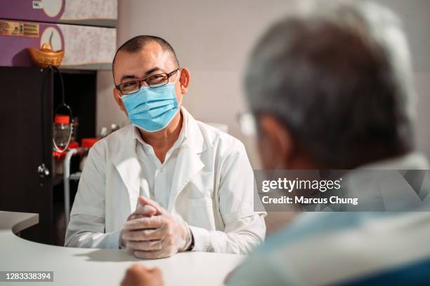 aziatische chinese mannelijke arts die zijn patiënt bij de chinese geneeskundewinkel bijstaat - chinese mask stockfoto's en -beelden