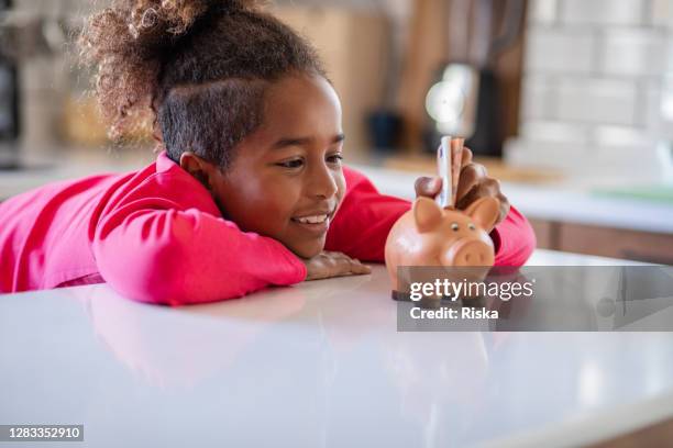 young girl putting money in a piggy bank - silver putter stock pictures, royalty-free photos & images